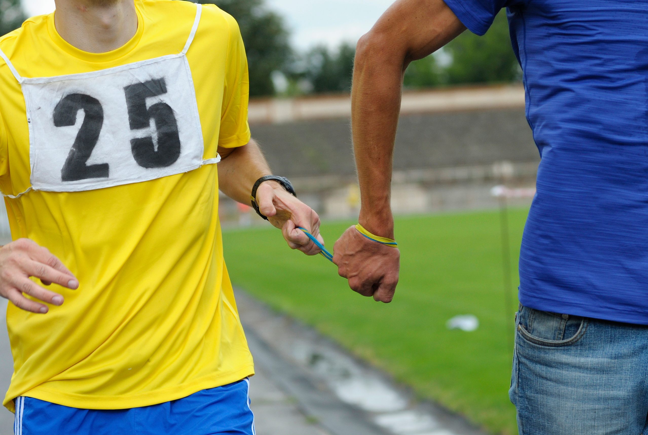 Way of leading blind runner: hand of disabled blind athlete (left) holds a hand of healthy one by rope
